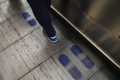 Low section of person standing on escalator