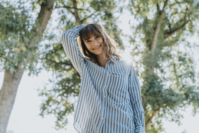 Portrait of smiling young woman standing against trees