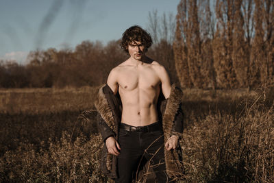 Full length of shirtless man standing on field