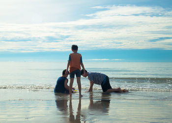 Rear view of men on beach against sky