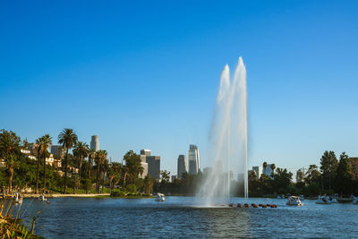 Fountain in lake against clear blue sky