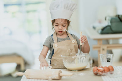 Girl holding ice cream on table at home