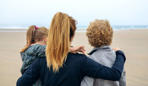 Rear view of women and girl walking on beach