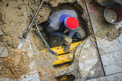 High angle view of man digging in sewer