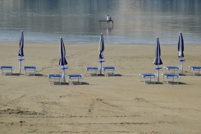High angle view of closed parasols and deck chairs at beach