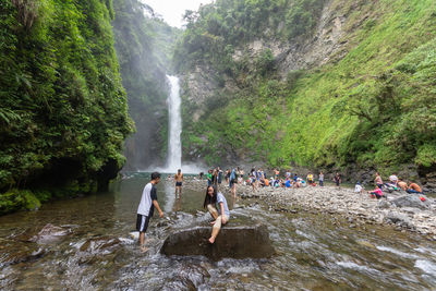 Group of people on rock against waterfall