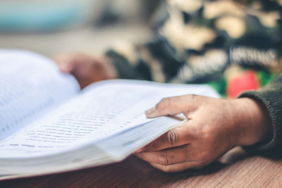 Close-up of hand holding book on table