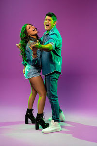 Full length of young woman standing against colored background