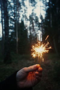 Close-up of hand holding sparkler at dusk