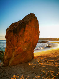 Rock formation on beach against clear sky