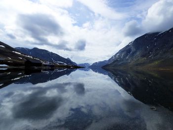 Scenic view of lake and mountains against cloudy sky