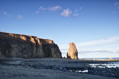 Rock formations on beach against blue sky