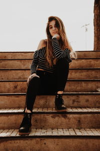 Portrait of girl sitting on steps against sky