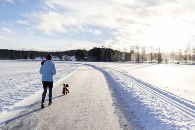 Rear view of woman walking on snow covered landscape