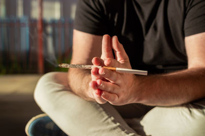 Midsection of man holding cigarette