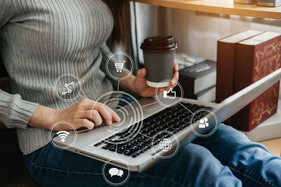 Midsection of man using mobile phone while sitting on table