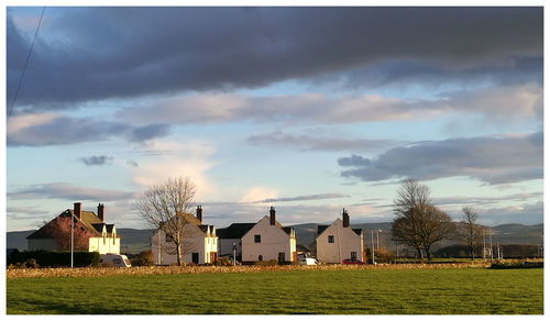 Houses and trees in city against storm clouds