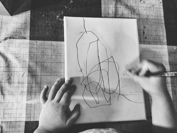 Cropped hands of child drawing on paper