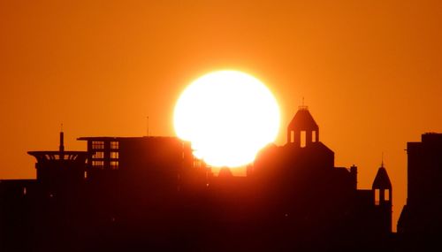 Silhouette city against orange sky