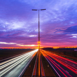 Light trails on road against sky at night