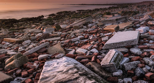 High angle view of rocks at beach against sky during sunset