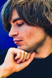 Close-up of young man with hand on chin looking away