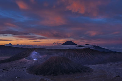 View of volcanic landscape against cloudy sky during sunset