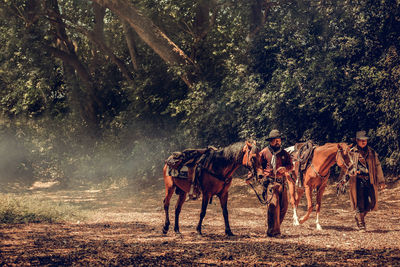 Full length of men with horse walking in forest