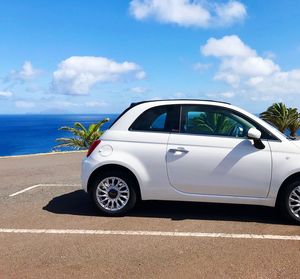 Car on road by sea against sky