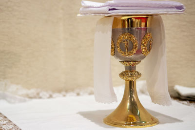 Close-up of cross on table against wall