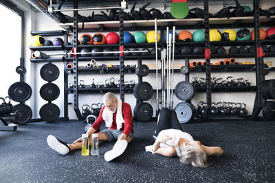 Exhausted senior couple recovering on the floor after working out in gym