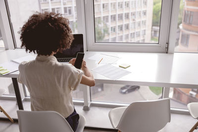 Rear view of woman using laptop at cafe