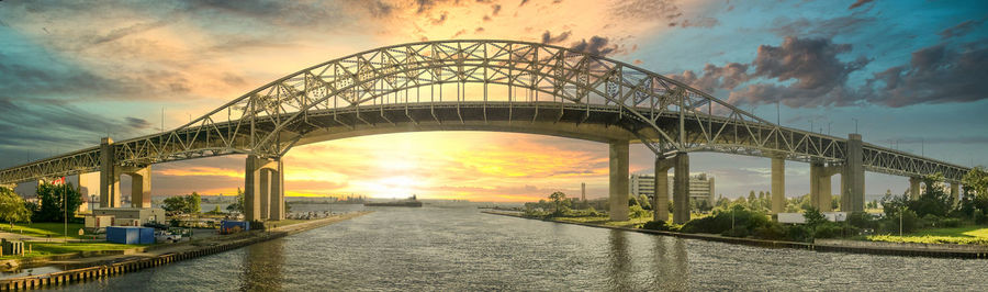 Bridge over river against cloudy sky during sunset