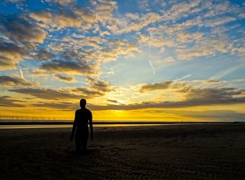 Silhouette man standing on beach against sky during sunset