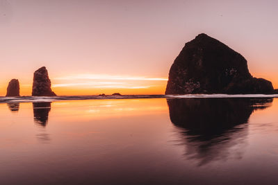 Scenic view of rock formation in sea against sky during sunset