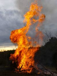 Bonfire on land against cloudy sky