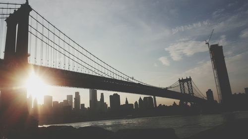 Bridge over river in city against sky during sunset