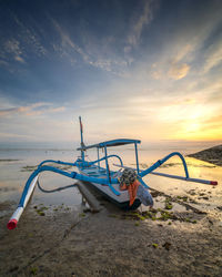 Deck chairs on beach against sky during sunset