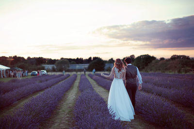 Rear view of couple kissing on field against sky