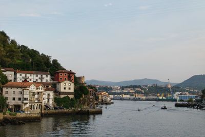 Buildings by sea against sky