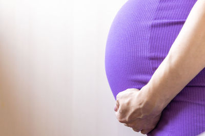 Close-up of woman hand against purple background