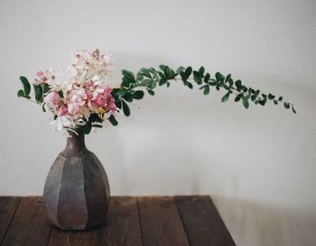 Close-up of vase on table against wall