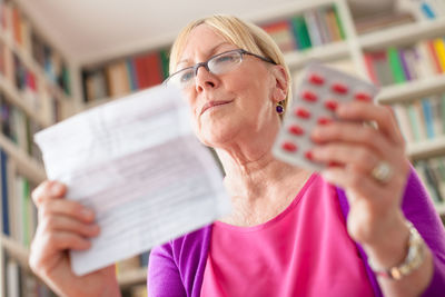 Low angle view of woman holding medicines and prescription