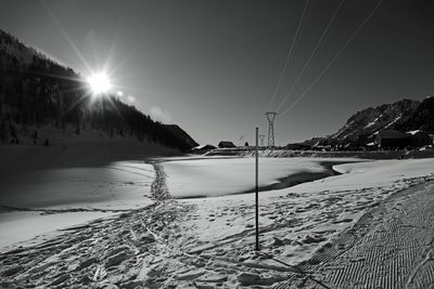 Scenic view of snow covered mountains against bright sun