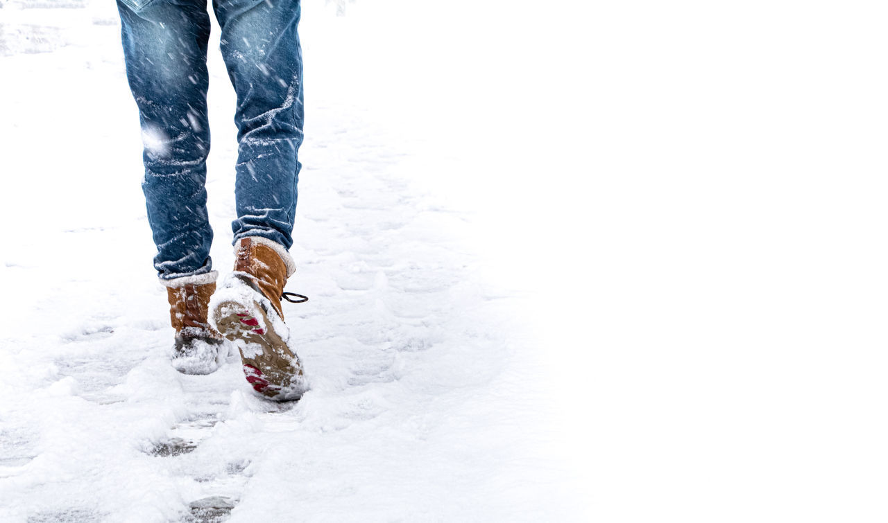 LOW SECTION OF WOMAN STANDING ON SNOW