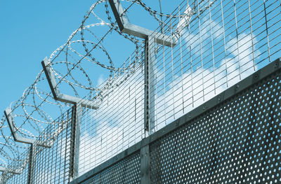 Low angle view of barbed wire fence against sky