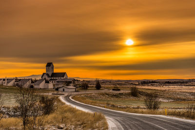 Road by land against sky during sunset