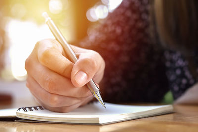 Close-up of woman hand holding paper on table
