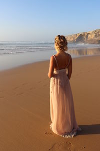 Rear view of woman at beach against sky