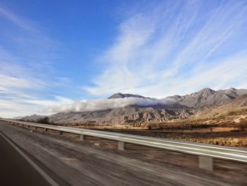 Road by mountains against sky